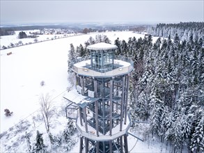 Observation tower in the centre of a snow-covered forest area seen from above