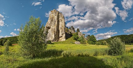 Striking limestone rock formation Burgstein with blue and white sky in the upper Altmuehltal surrounded by green vegetation