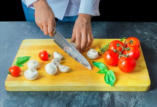 Professional chef cuts vegetables with a sharp knife from Damascus steel.