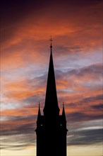 Silhouette of the late Gothic church tower of Radolfzell Minster against a dramatic orange and red sky at sunrise