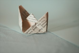 A sepia-toned origami paper boat with soft shadows on a light surface