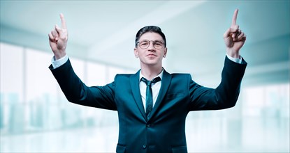 Confident boss in a business suit celebrates victory in the office. His arms are raised and he is smiling. Business motivation.