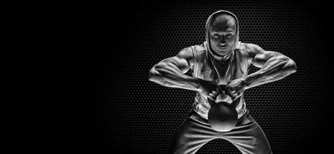Portrait of an athlete pulling a kettlebell to his chin. The concept of sport and healthy lifestyle.