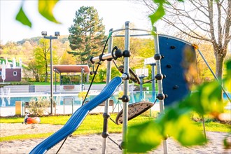 Children's playground with climbing frame and slide in the shade of trees