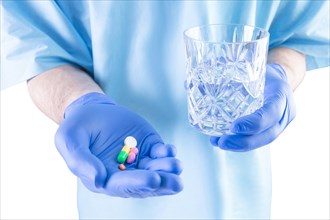The doctor holds out pills and a glass of water. Medical concept.