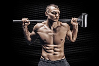 Portrait of an athlete with a sledgehammer on his shoulders. The concept of sport and healthy lifestyle.