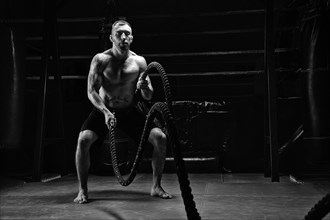 The athlete works with crossfit ropes in the gym. The concept of sports
