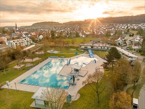 Aerial view of an outdoor pool in the village on a cloudy day with visible swimming pool and slide