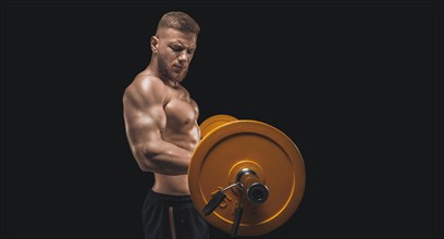 Young muscular guy pumps his biceps with a barbell on a black background. Fitness and nutrition concept.