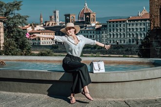 Portrait of a charming girl sitting near a fountain in Florence. View of Santa Maria del Fiore. Tourism concept. Italy.