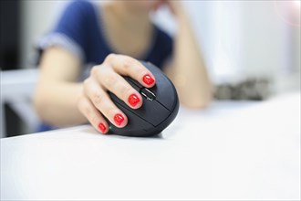 Girl's hand uses a vertical ergonomic joystick of a computer mouse. working at the computer