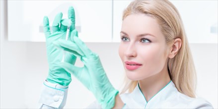 Portrait of a blonde girl in a medical gown with a syringe in her hands. Vaccination concept.