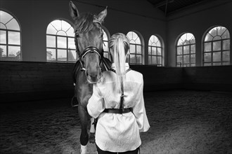 Image of a blonde woman in the form of a rider from the back. Horse racing and equestrian sport concept.