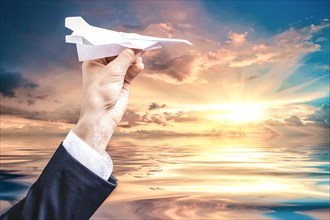 Image of a hand holding a paper airplane. Tourism concept.