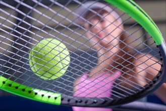 Image of a tennis ball on the background of the strings of the racket. Sports concept.