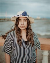 Portrait of attractive woman in hat on the pier looking at camera. Portrait of young tourist woman in hat on a pier