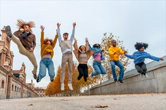 Low angle view photo of a group of multi-ethnic friends jumping in an urban park