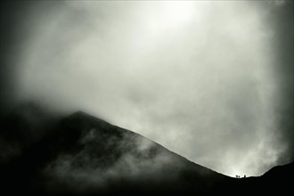 Mountaineer on mountain ridge with dramatic clouds