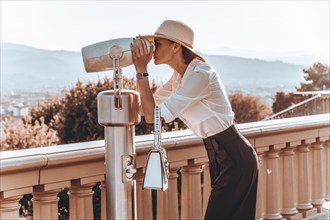 Girl looks at the panorama of Florence through a binoscope. The concept of tourism