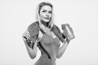 Charming model posing in the studio with a shaker in her hands and a towel around her neck.