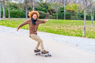 Redheaded curly hair Young man skating in a park in autumn