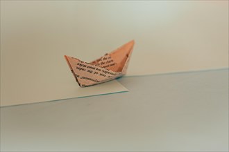 An origami paper boat with a minimalist design casting a shadow on a blue surface