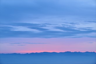 Dawn with pink and blue colours over a mountainous silhouette