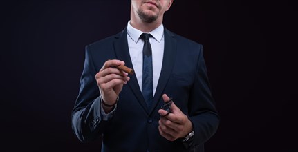 Image of an adult stylish man in a suit with a cigar. Cigar clubs concept.