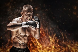 Mixed martial artist posing against the backdrop of fire and smoke. Concept of mma