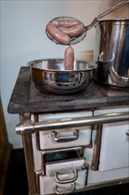 A Bowl with Luganighe Sausage on an Old Kitchen Stove in Lugano