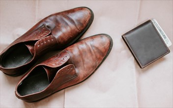 Brown men's shoes made of genuine leather and a brown leather wallet with money