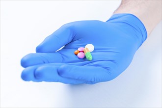 The doctor holds out pills lying on a blue glove. Medical concept.