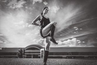 Beautiful young runner warms up on the soccer field before the race. Sports concept.