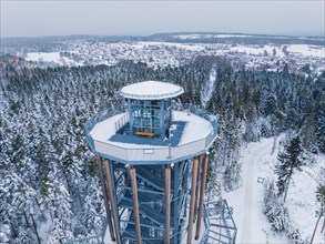 Modern observation tower rises out of a snow-covered forest