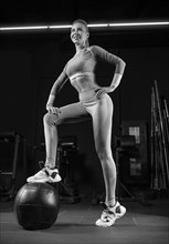 Charming blonde posing in the gym with a fitness ball. Front view. The concept of sports