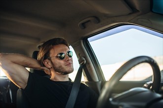 Young handsome male driver tired of sitting behind the wheel