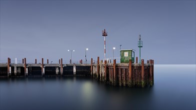Long exposure of the illuminated harbour watchman's house at dusk during the blue hour at the harbour entrance of List on Sylt