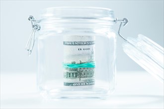 Pack of hundred-dollar bills lies in a glass jar. The concept of savings during the crisis.