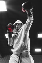 Brutal athlete boxing in the ring in a white hoodie covered with a hood. Mixed martial arts concept. High image quality