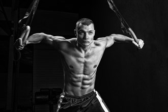 The athlete pulls himself up on the gymnastic rings. The concept of sport and healthy lifestyle.