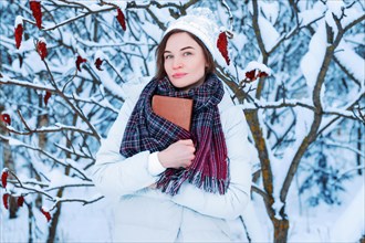 The girl walks through the winter forest. She covered her face with a book. Learning concept. Winter's tale.