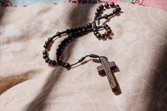 A rosary with a cross lying on a fabric surface in a softly lit environment