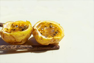 Halved passion fruit and dark wooden spoon on a light background. Close up