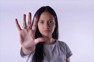 Young latin woman in casual outfit making the hand stop sign against lilac studio background. Concept WomenÂ´s day