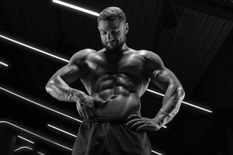 Portrait of an athletic muscular man who checks the condition of the abdominal muscles. Fitness concept.