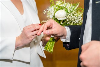 Woman putting the ring on the groom at a wedding