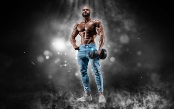 Isolated athlete on a background of smoke with small dust particles. Bodybuilding concept.