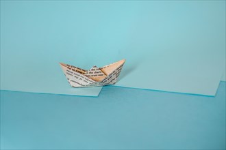 An origami paper boat on a two-tone background casting a long shadow