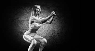 Charming girl is training in the gym with a rubber band. The concept of bodybuilding