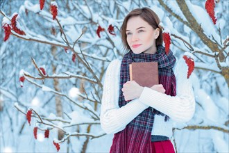 Image of a beautiful woman standing in a winter forest with a book in her hands. The concept of a miracle